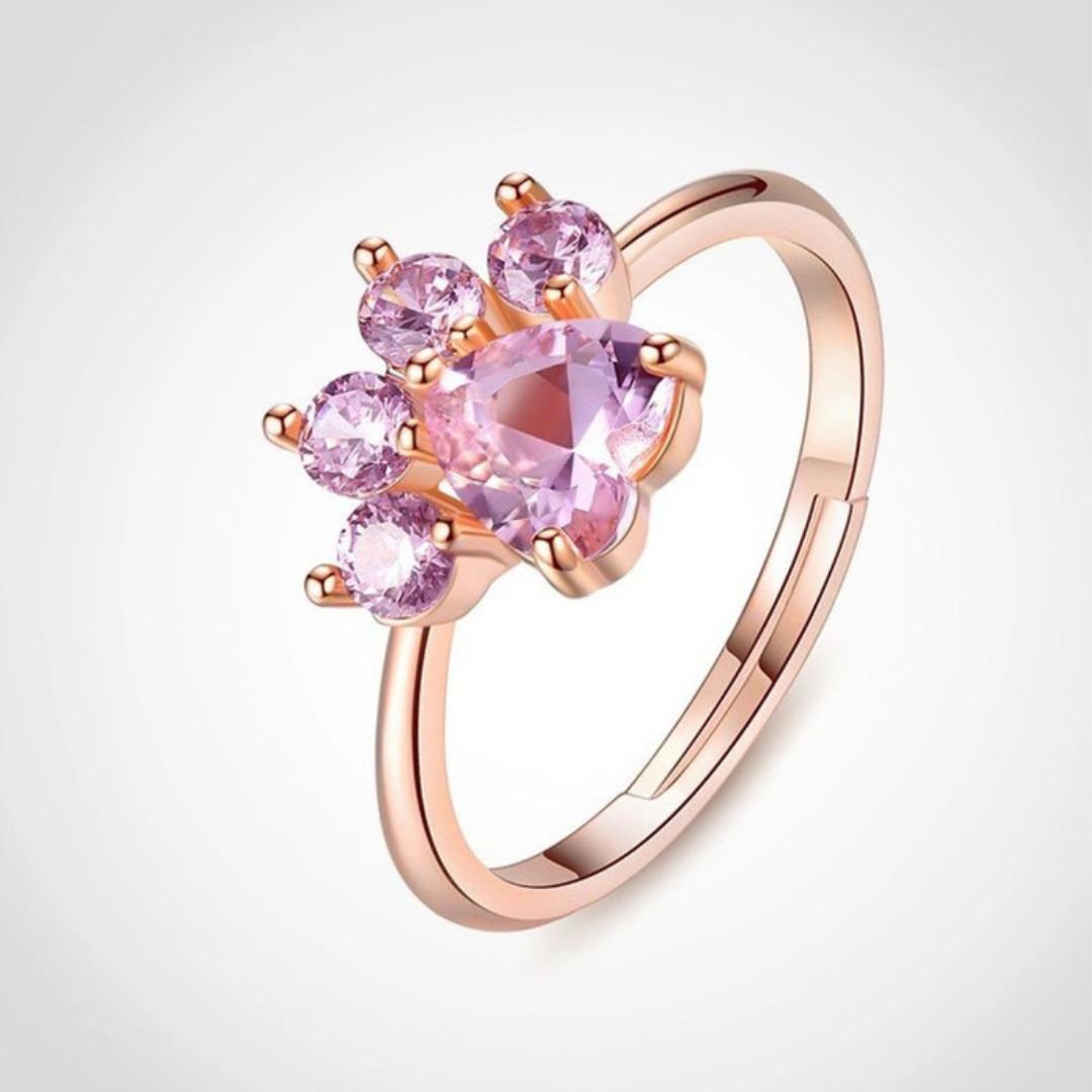 El Anillo Patita rosa es un anillo de oro rosa con cinco piedras preciosas rosas en un diseño con forma de pata: un centro en forma de corazón y cuatro dedos redondos. Perfecto para los amantes de las mascotas.