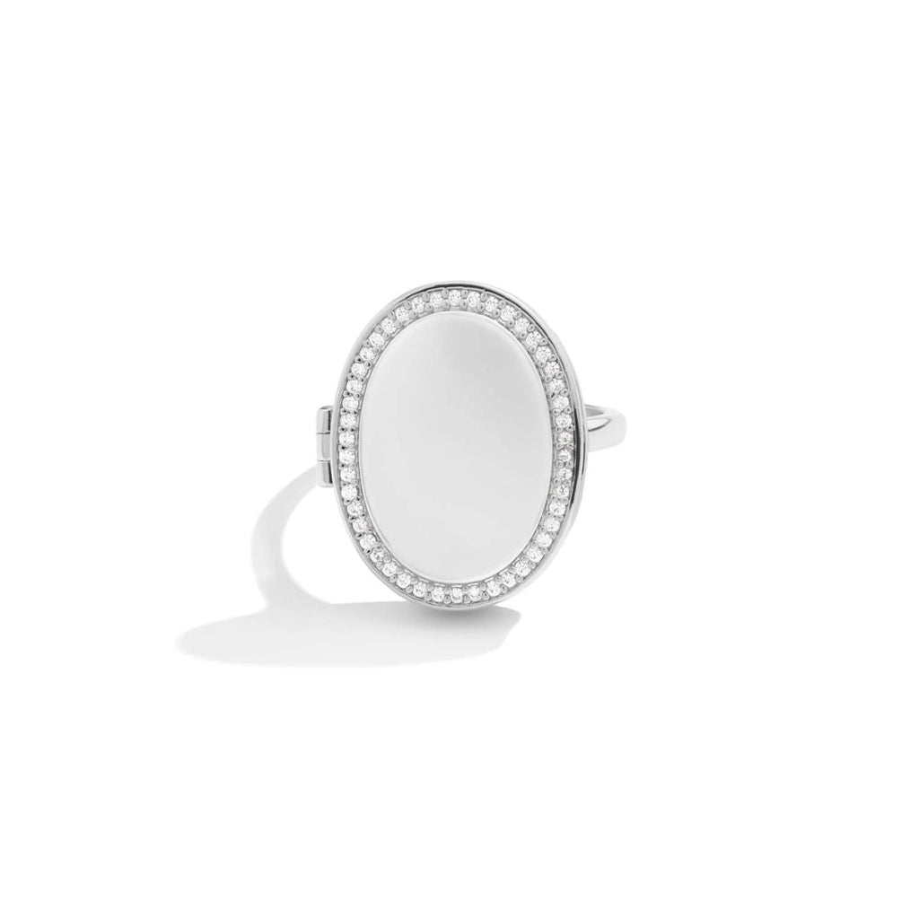 Anillo personalizado con foto en plata, forma ovalada y piedra central blanca lisa, rodeada de piedras claras brillantes. Exhibido sobre fondo blanco liso.
