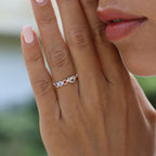 Primer plano de la mano cuidada de una mujer que lleva el Anillo personalizado Lazos del corazón, adornado con piedras de nacimiento de colores, sostenida cerca de su cara con los labios suaves visibles en el fondo.