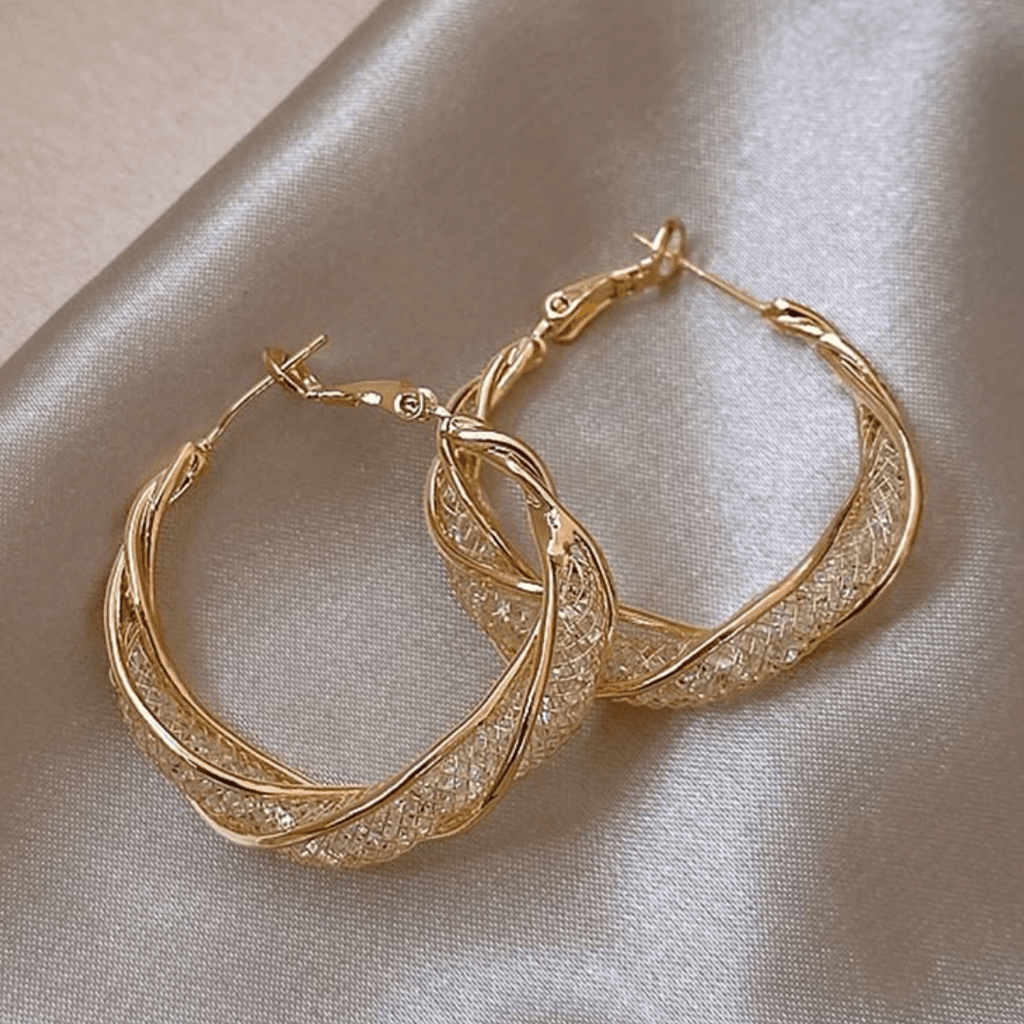 Aretes colgantes en espiral de acero inoxidable dorado, con detalles torcidos y textura, sobre fondo satinado claro.