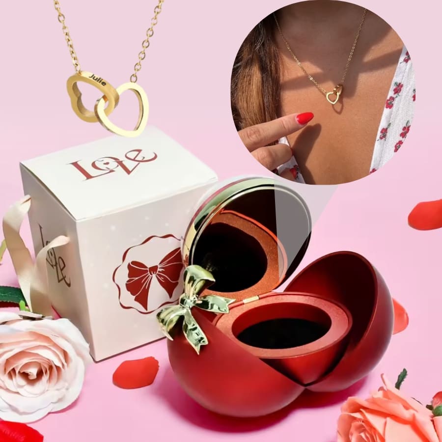 La Caja Corazón con rosa eterna y collar corazón personalizado se muestra con una caja de regalo Love blanca; un recuadro muestra el collar lucido con un vestido floral y uñas rojas. Rosas, entre ellas una rosa eterna, decoran la escena.
