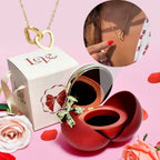La Caja Corazón con rosa eterna y collar corazón personalizado se muestra con una caja de regalo Love blanca; un recuadro muestra el collar lucido con un vestido floral y uñas rojas. Rosas, entre ellas una rosa eterna, decoran la escena.