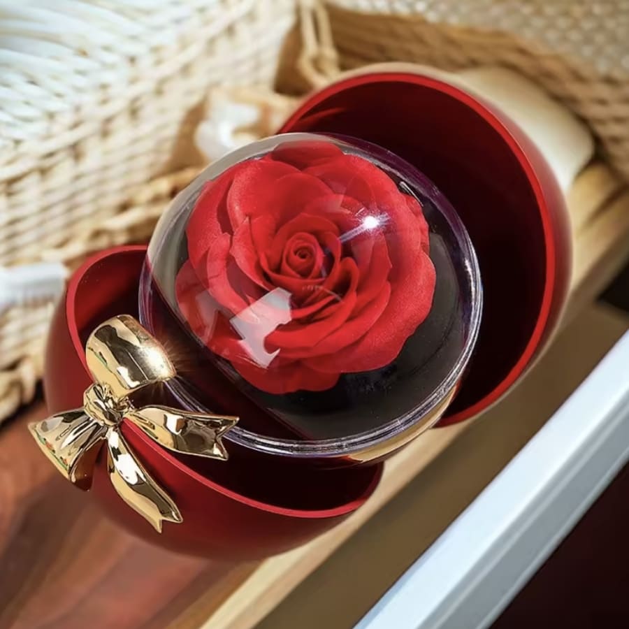 La Caja Corazón con rosa eterna y collar corazón personalizado presenta una rosa preservada en una cúpula transparente, colocada en una caja roja en forma de corazón con un lazo dorado, perfecta para regalar.
