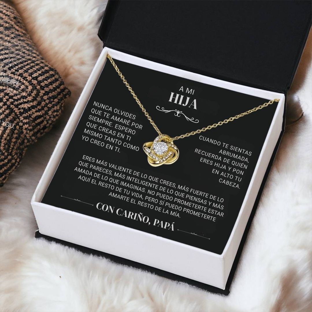 El collar "A mi hija" - Con cariño Papá, con un colgante de corazón, se presenta en una caja de regalo negra con un sentido mensaje en español de padre a hija -un regalo perfecto papá a hija- expuesto sobre una suave superficie blanca.