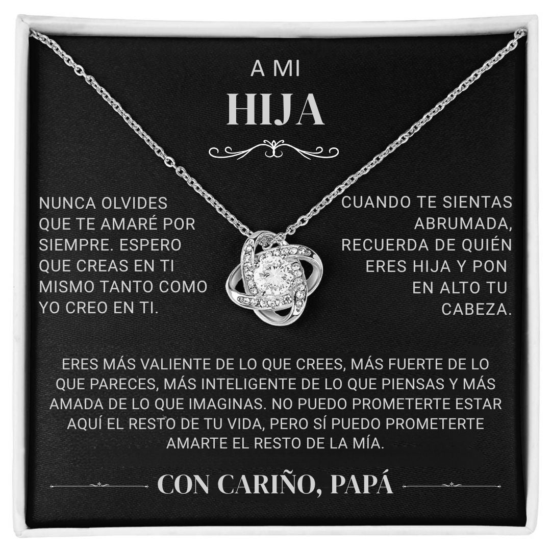 El collar "A mi hija" - Con cariño Papá es un collar de plata con un colgante entrelazado y una gema central, sobre una tarjeta negra con un sentido mensaje en español de papá a hija, expresando amor, ánimo y apoyo.