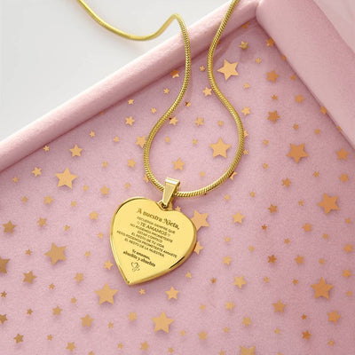 El collar "A nuestra nieta" de corazón, grabado con un mensaje en español, descansa sobre una superficie rosa con confeti de estrellas doradas en un joyero-un regalo ideal abuelos nieta.