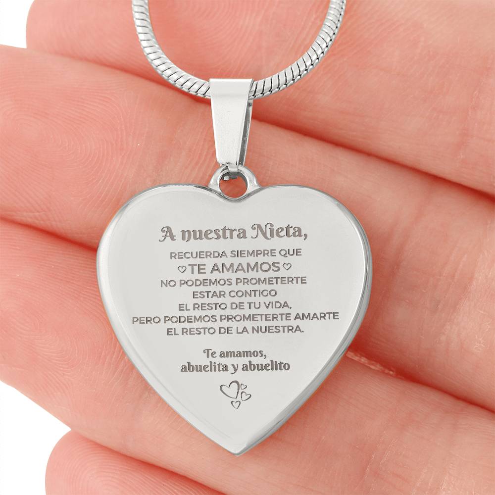 Una mano sostiene el Collar "A nuestra nieta" de corazón, grabado en español con un sentido mensaje de los abuelos-un memorable regalo abuelos nieta que simboliza su amor duradero y la promesa de quererla siempre.