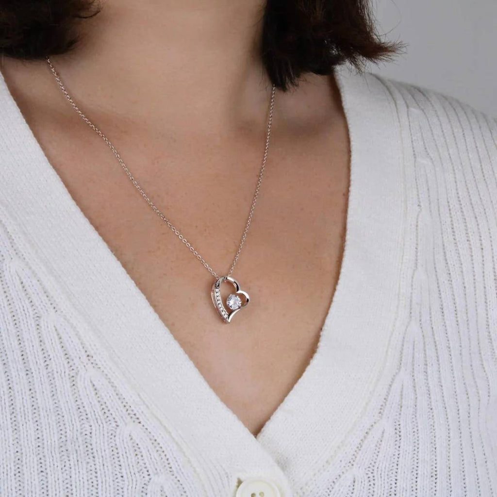 Una persona lleva un cárdigan blanco de canalé con Collar Amor eterno, un colgante en forma de corazón con una pequeña piedra preciosa, un regalo ideal para mujeres.