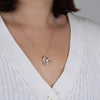 Una persona lleva un cárdigan blanco de canalé con Collar Amor eterno, un colgante en forma de corazón con una pequeña piedra preciosa, un regalo ideal para mujeres.