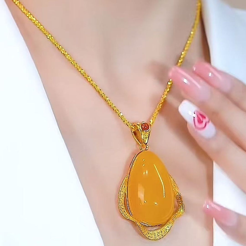 Una persona lleva el Collar amuleto de piedra ágata amarilla con un gran colgante de lágrima amarilla. Sus uñas florales rosas descansan cerca, y su atuendo blanco irradia energía positiva junto a esta joya retro.