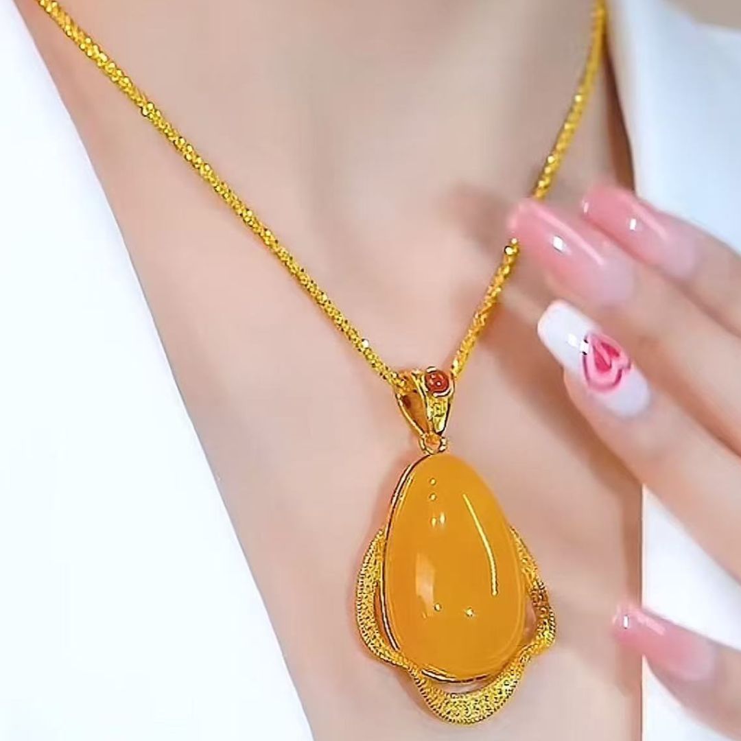 Una persona lleva el Collar amuleto de piedra ágata amarilla con un gran colgante de lágrima amarilla. Sus uñas florales rosas descansan cerca, y su atuendo blanco irradia energía positiva junto a esta joya retro.