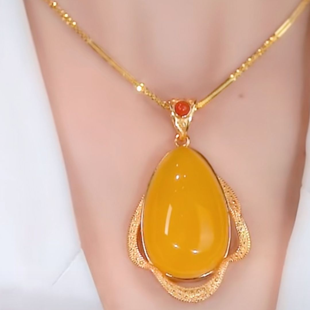 El collar amuleto de piedra ágata amarilla luce un gran colgante ovalado y una pequeña gema naranja encima, transmitiendo energía positiva sobre piel clara.