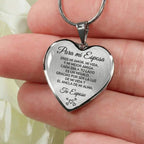 Una mano sostiene el "Collar con colgante Para mi esposa", un colgante de plata en forma de corazón grabado en español, que expresa amor y gratitud a una esposa, firmado "Tu Esposo" y decorado con pequeños corazones grabados.