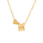 El Collar con inicial y corazón es un collar dorado con un dije de letra "M" y un pequeño corazón, ambos en una delicada cadena dorada, presentado sobre fondo blanco-un regalo personalizado perfecto.
