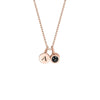 Collar con inicial y foto en oro rosa con dos dijes redondos: uno grabado con la letra A y otro decorado con una pequeña gema negra.