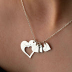 Primer plano del collar Corazones de familia, con cuatro colgantes en forma de corazón grabados con distintos nombres, apoyados en el cuello. Este elegante collar personalizado es ideal para tener cerca a sus seres queridos.