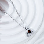 El Collar de corazón con foto, en color plateado, es ideal para collares personalizados y guardar recuerdos especiales. Presentado sobre un fondo blanco texturizado.