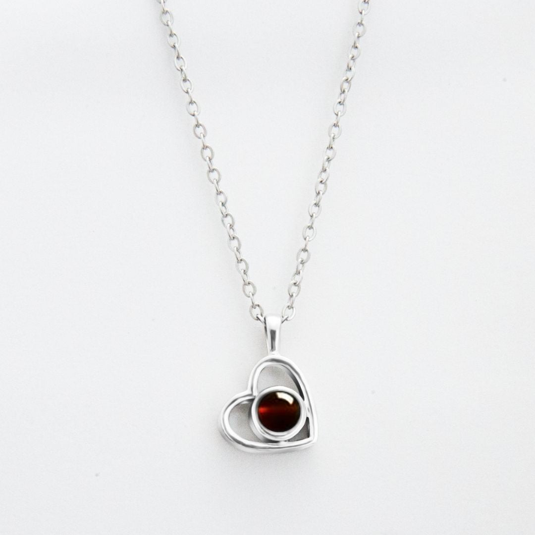 El Collar de corazón con foto es una cadena plateada con dije de corazón, ideal para recuerdos especiales o como uno de nuestros collares personalizados. El fondo es blanco.