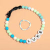 El Collar de cuentas personalizado para mascotas + Pulsera gratis, con broche negro y cuentas LUKE, se exhiben juntos sobre fondo durazno-un regalo ideal para amantes de mascotas.