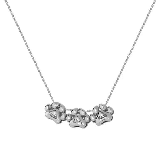El Collar de huellitas de mascotas personalizado en color plateado lleva tres dijes en forma de huella, cada uno grabado con nombres como Olivia, Alex y Mara. Un collar personalizado ideal para celebrar a tus seres queridos.