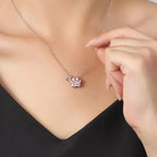 Una mujer con top negro muestra el "Collar de huellitas de mascotas personalizado", con un colgante en forma de pata grabado con "Lucky", mientras sujeta suavemente la cadena cerca de su clavícula.
