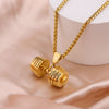 El Collar de pesa personalizado, un dije dorado en forma de mancuerna con nombres grabados en ambos lados, se exhibe sobre satén beige y un soporte blanco-regalo perfecto para papá en el Día del Padre.