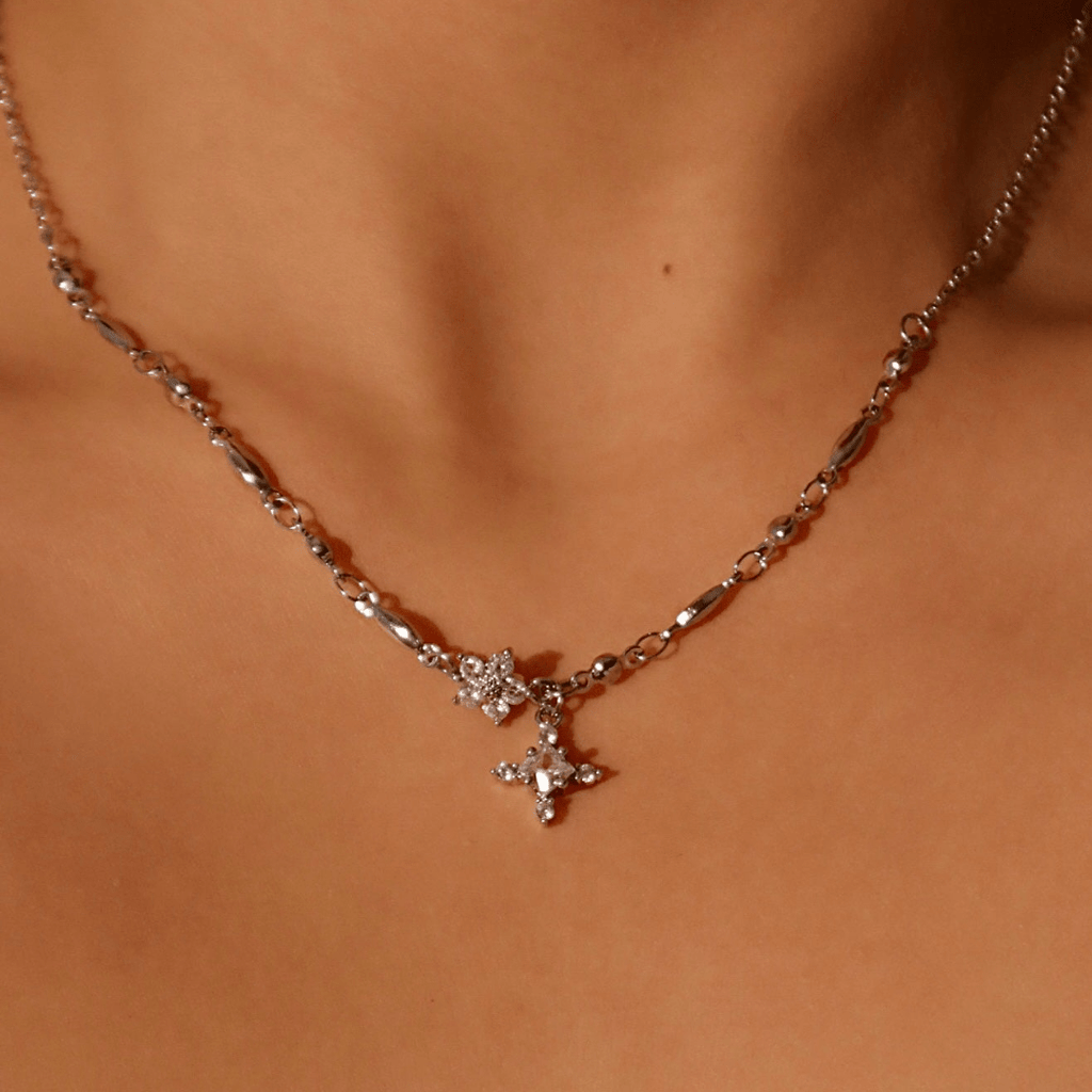 Detalle del collar Destello de estrella, un collar plateado con dos colgantes en forma de estrella con piedras transparentes, que se lleva alrededor del cuello.