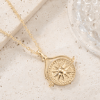 Collar giratorio Sol y Luna "Hatha" con dije circular texturizado y estrella en relieve, expuesto sobre una piedra beige claro junto a un objeto decorativo transparente.