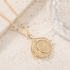 Collar de oro con un colgante redondo y texturizado en el que aparece una luna creciente sobre una piedra beige junto a un cristal con motivo de burbujas. Inspirado en el collar giratorio Sol y Luna "Hatha".