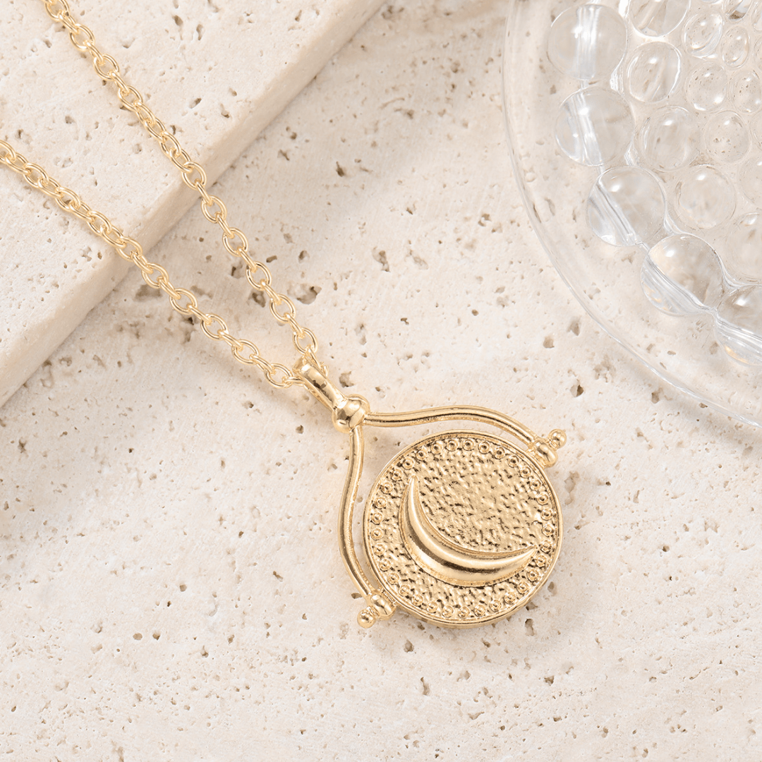Collar de oro con un colgante redondo y texturizado en el que aparece una luna creciente sobre una piedra beige junto a un cristal con motivo de burbujas. Inspirado en el collar giratorio Sol y Luna "Hatha".