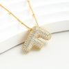 El Collar Inicial Bubble - ¡Llévate 2 por el precio de 1! en oro, con colgante de letra F y brillantes, se exhibe sobre una superficie blanca. Un regalo personalizado ideal para esa persona especial.