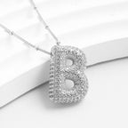 Collar Inicial Bubble: elegante collar en plata con colgante letra B decorado con cristales. ¡Llévate 2 por el precio de 1! Perfecto como regalo personalizado. Se muestra sobre un fondo blanco sofisticado.