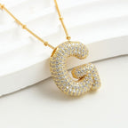 El Collar Inicial Bubble luce una gran letra inicial G con cristales brillantes sobre fondo blanco texturizado. ¡Lévate 2 por el precio de 1 y crea el regalo personalizado perfecto!.