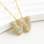 El Collar Inicial Bubble, ¡llévate 2 por el precio de 1!, es un elegante accesorio dorado con iniciales y brillantes piedras claras, ideal como regalo personalizado para cualquier ocasión.