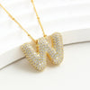 El Collar Inicial Bubble, ¡llévate 2 por el precio de 1!, es un elegante accesorio dorado con iniciales y brillantes piedras claras, ideal como regalo personalizado para cualquier ocasión.