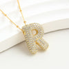 El Collar Inicial Bubble, con colgante R enchapado en oro y diamantes brillantes, se exhibe sobre fondo blanco. ¡Llévate 2 por el precio de 1! Ideal como collar con inicial y regalo personalizado inolvidable.