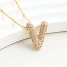 Cargar imagen en el visor de la galería, El Collar Inicial Bubble, con dije en forma de V y brillantes piedras claras, se muestra sobre una superficie blanca-¡llévate 2 por el precio de 1! Un regalo personalizado ideal.