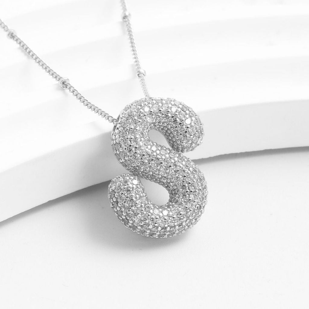 El Collar Inicial Bubble es de plata, con colgante en forma de letra S decorado con strass. Es un regalo personalizado ideal. Disponible: ¡llévate 2 por el precio de 1! Se presenta sobre fondo blanco.