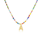 Collar Inicial colorido - ¡Llévate 3 por el precio de 1! Un collar con cuentas de colores y dije dorado con letra A, ideal como regalo para amigas. Se muestra sobre fondo blanco.