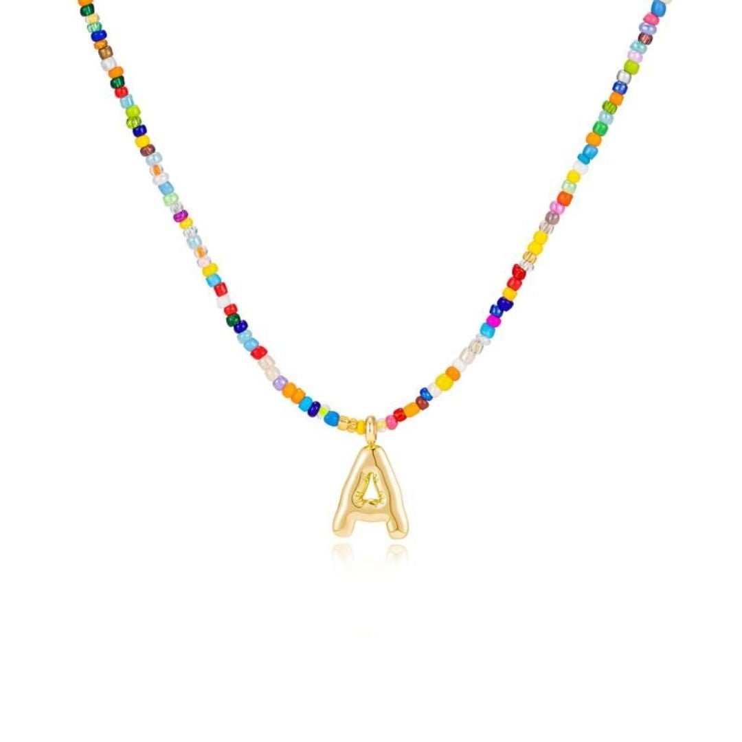 Collar Inicial colorido - ¡Llévate 3 por el precio de 1! Un collar con cuentas de colores y dije dorado con letra A, ideal como regalo para amigas. Se muestra sobre fondo blanco.