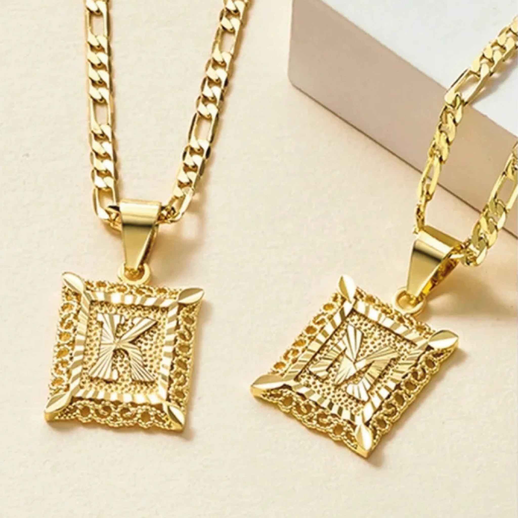 El collar IZAC con inicial personalizada incluye dos collares de oro con gruesas cadenas estampadas y colgantes rectangulares con una inicial K o M en relieve, cada uno de ellos ribeteado con un detalle texturizado que le da un toque especial.