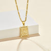 El collar IZAC con inicial personalizada es un collar de oro con un colgante rectangular de filigrana con la letra A, que aparece sobre un fondo crema junto a un bloque rectangular blanco.