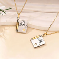 Dos medallones dorados y plateados en forma de libro con detalles de corazón cuelgan de cadenas doradas. Cada uno "Collar Libro a mi nieta - Tú siempre estarás en mi corazón" presenta un dibujo lineal de pareja y un corazón recortado. Perfecto regalo para nieta, se muestra sobre fondo beige.