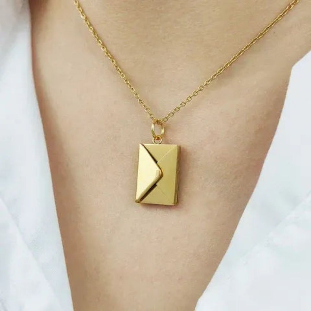 Un primer plano del collar de oro "Mi carta de amor" con un colgante rectangular en forma de sobre, que se lleva en el cuello sobre un top blanco: un regalo ideal para esposa.