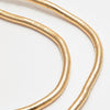 Primer plano de dos brillantes cadenas multiuso moldeables Collar de oro fabricadas en acero inoxidable, expuestas sobre una superficie blanca con sutiles curvas y un diseño texturizado y segmentado estilo serpiente.