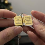 Una persona sostiene un collar "Mi Pequeña Estrella" con dije tipo libro abierto, grabado en español: Cuando te sientas no amada, recuerda que eres amada sin medida-un regalo significativo y conmovedor.