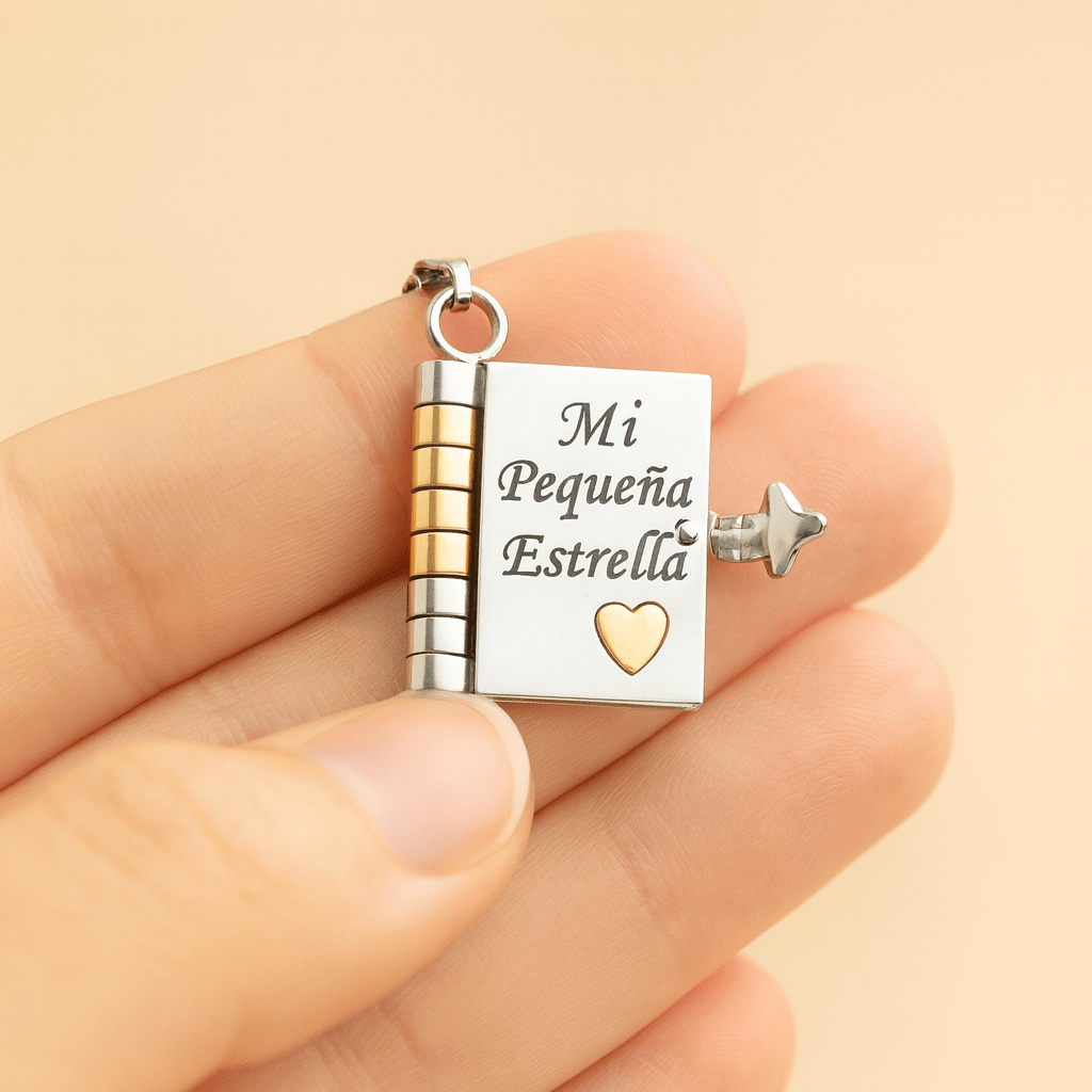 Una mano sostiene el "Collar para hija - Mi Pequeña Estrella", un pequeño medallón en forma de libro de oro y plata con un corazón de oro, grabado con "Mi Pequeña Estrella" y un pequeño colgante en forma de estrella: un regalo significativo ideal para hija.