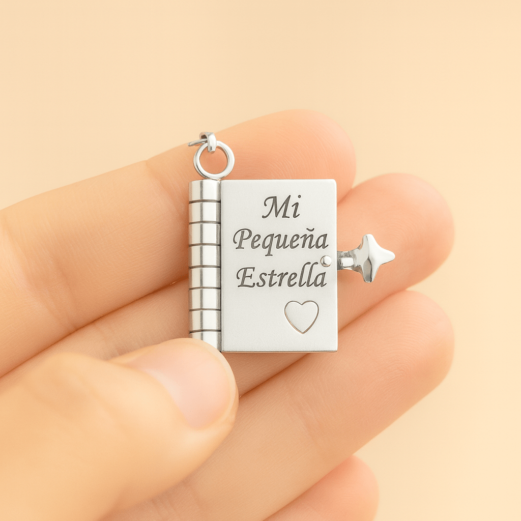 Una mano sujeta el Collar para hija - Mi Pequeña Estrella de plata, con forma de libro y "Mi Pequeña Estrella" y un corazón grabados, además de un cierre de estrella- un regalo significativo ideal para tu hija.
