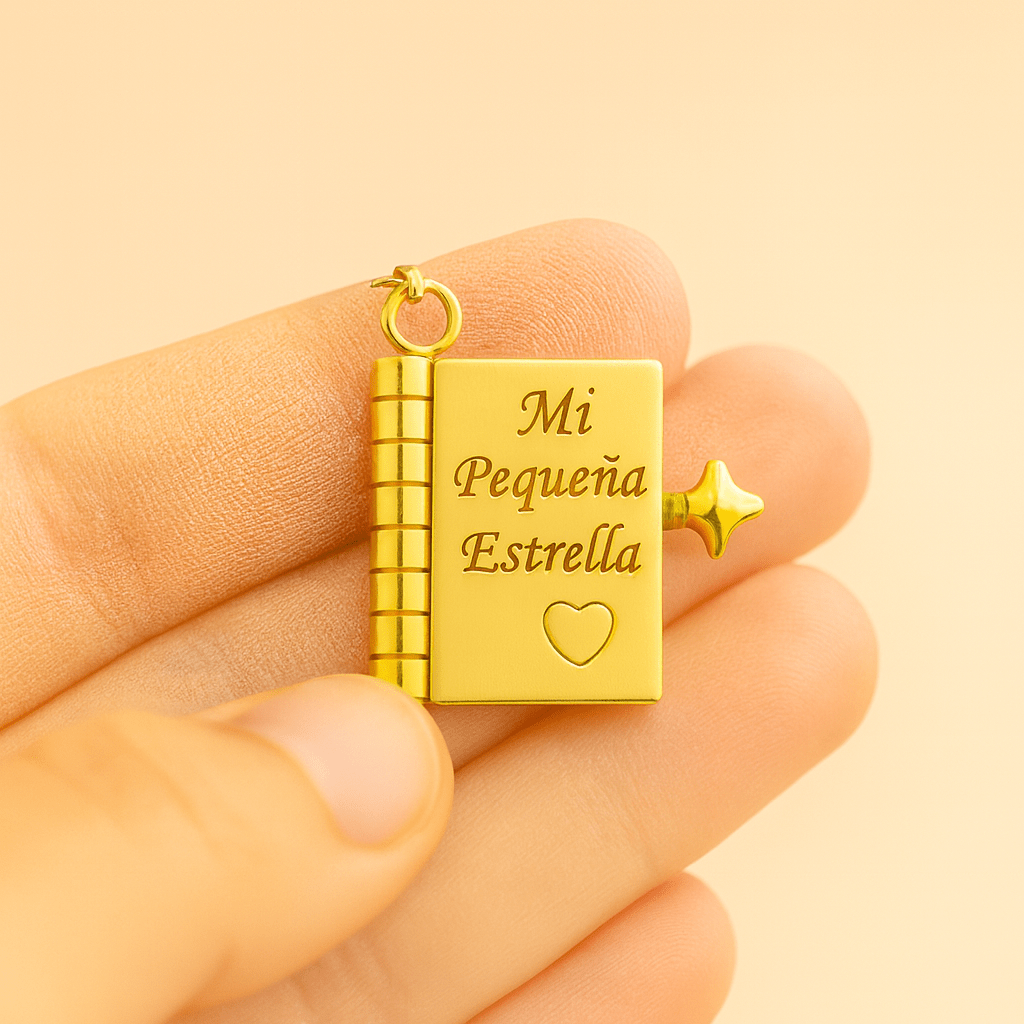 Una mano sostiene el Collar para hija - Mi Pequeña Estrella, un medallón de oro con forma de pequeño libro grabado con "Mi Pequeña Estrella" y un corazón. Este collar de oro incluye una pequeña estrella y una anilla para enganchar a una cadena: un regalo significativo.