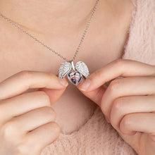 Cargar imagen en el visor de la galería, Una persona sostiene un collar personalizado con foto en forma de corazón plateado, abierto para mostrar una pequeña foto de dos personas en su interior. Lleva puesto un top rosa suave y esponjoso.
